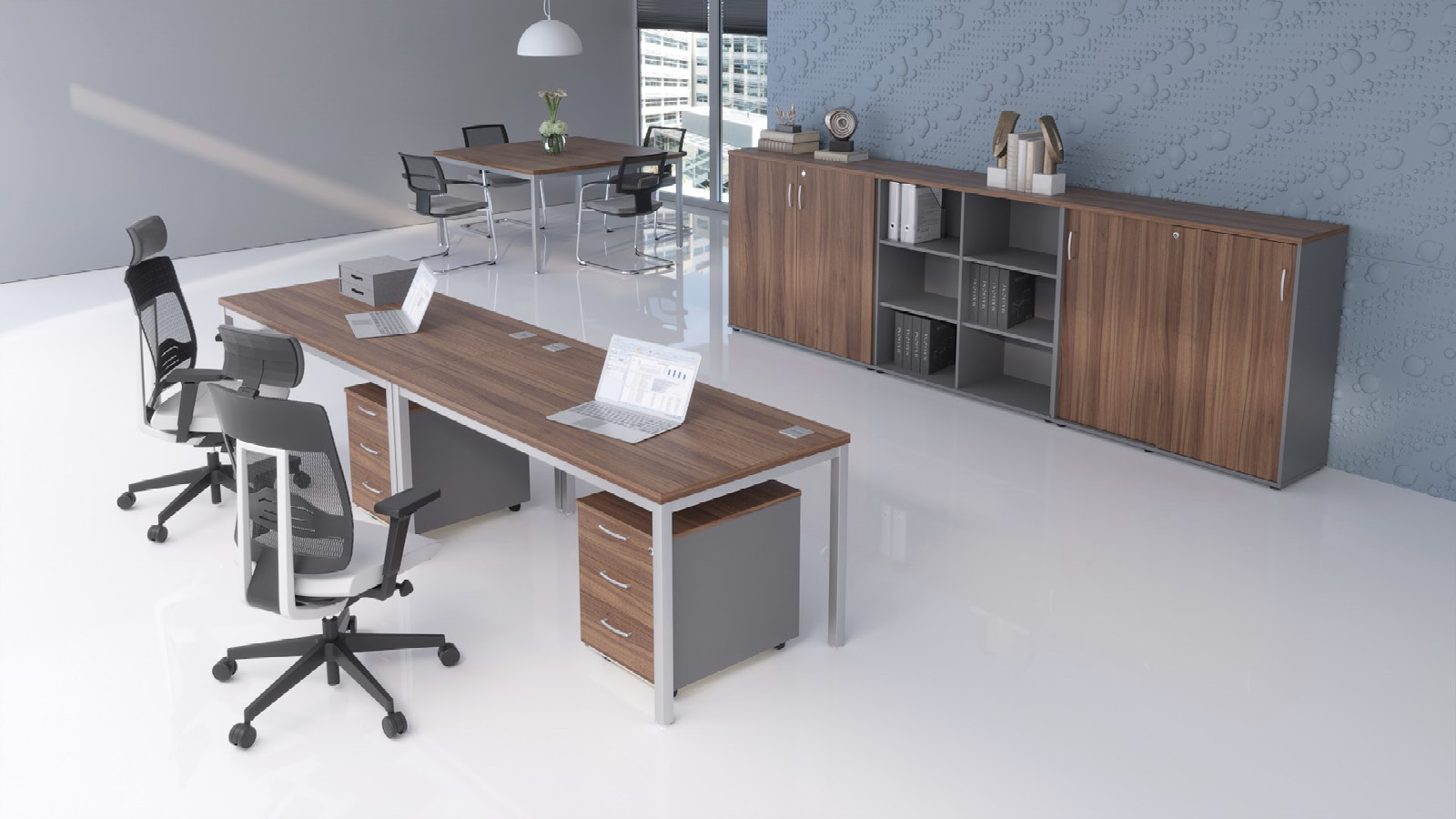 Biuro wyposażone w stanowiska pracy i miejsce do spotkań. Z przodu biurka z kontenerkami i szafą, z tyłu - stół z krzesłami.